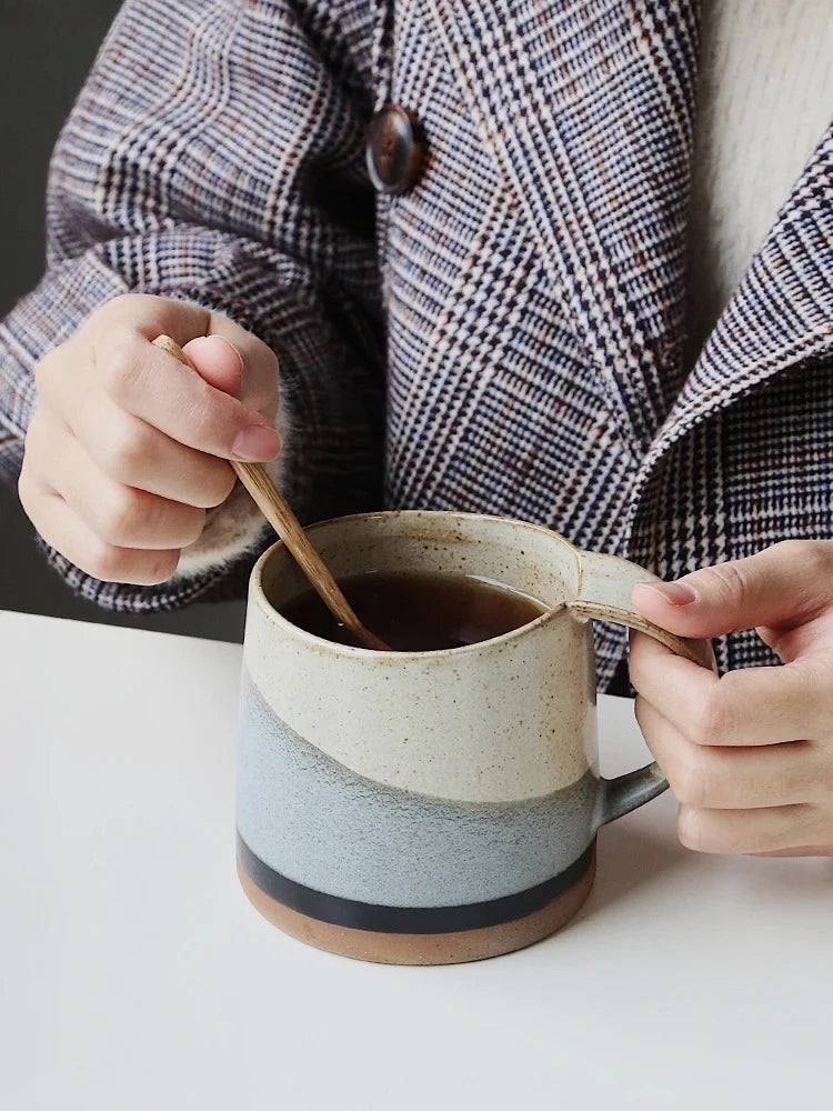 Person Stirring And Drinking Hot Beverage Out Of Dark Tides Ceramic Mug That Looks Like The Ocean Shore