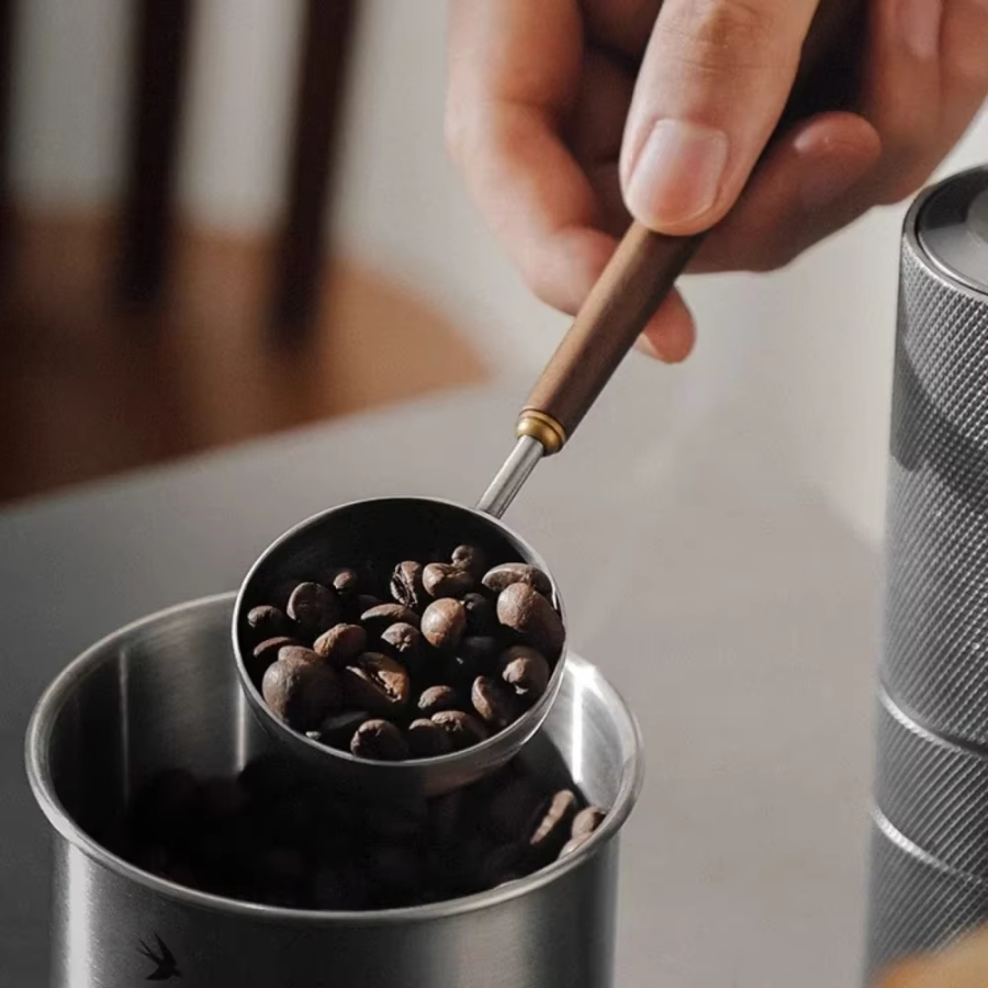 Barista Using Sleek Wood And Stainless Steel Coffee Scoop For Whole Beans And Coffee Making