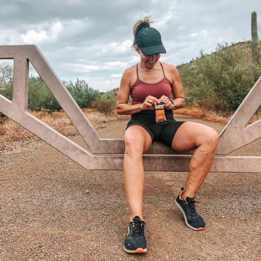 Woman Outdoors After Exercising Eating A Mango Coconut Kate's Energy Bar